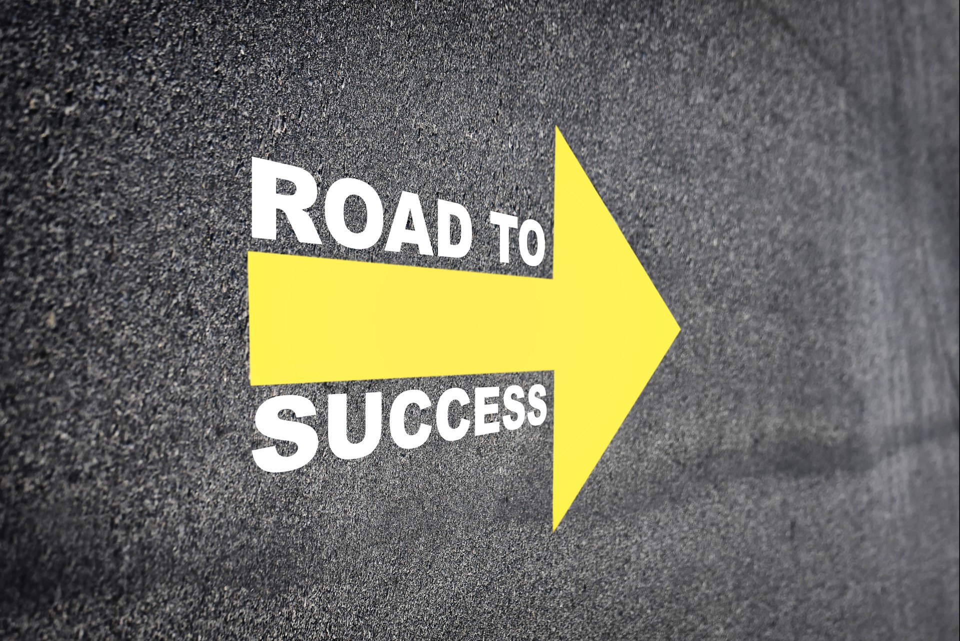 Road to success with yellow arrow marking on road surface